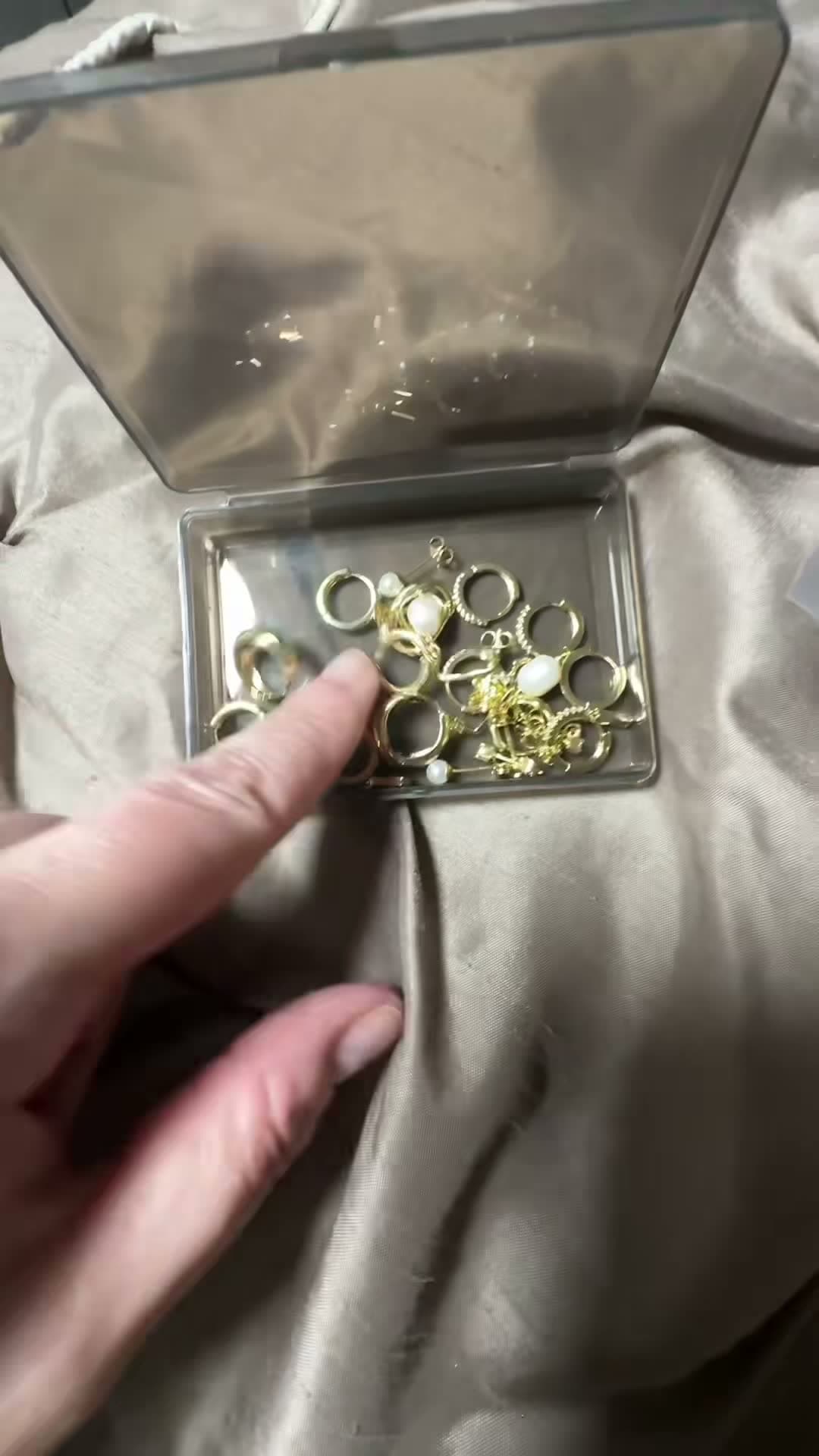 Hands sorting through a gold jewelry set on fabric
